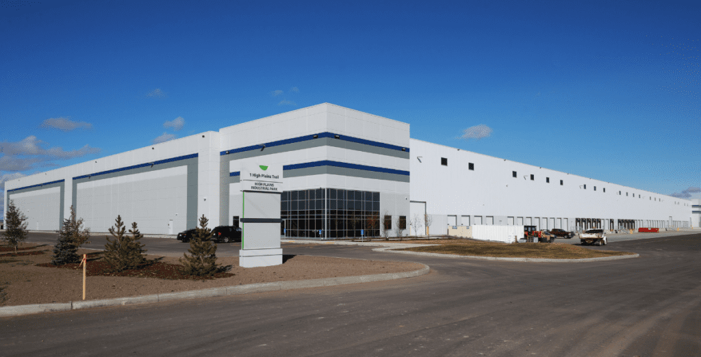 Exterior image of front sign with address and industrial building with vast loading doors on the right located at 1 High Plains Trail in Balzac (Calgary), Alberta. 